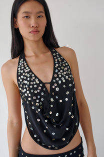 Woman wearing a black halter top with silver embellishments on a white background