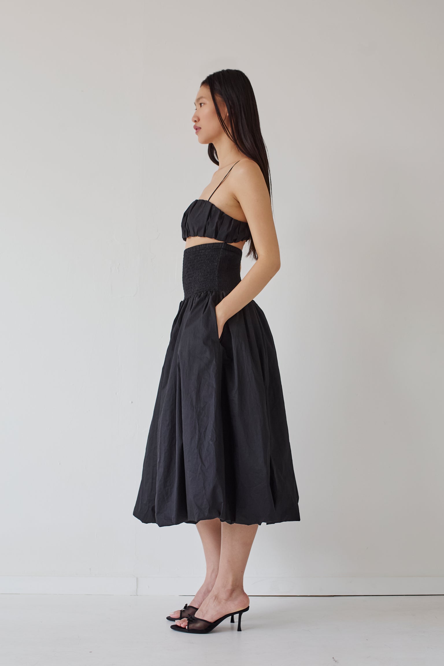 Woman wearing a black puffy bralette and a matching puffy skirt against a white background.