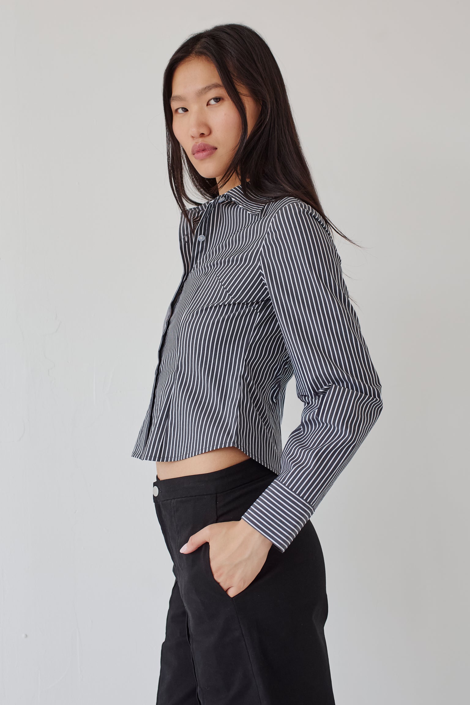 Woman wearing a black and white striped shirt paired with black pants against a plain background