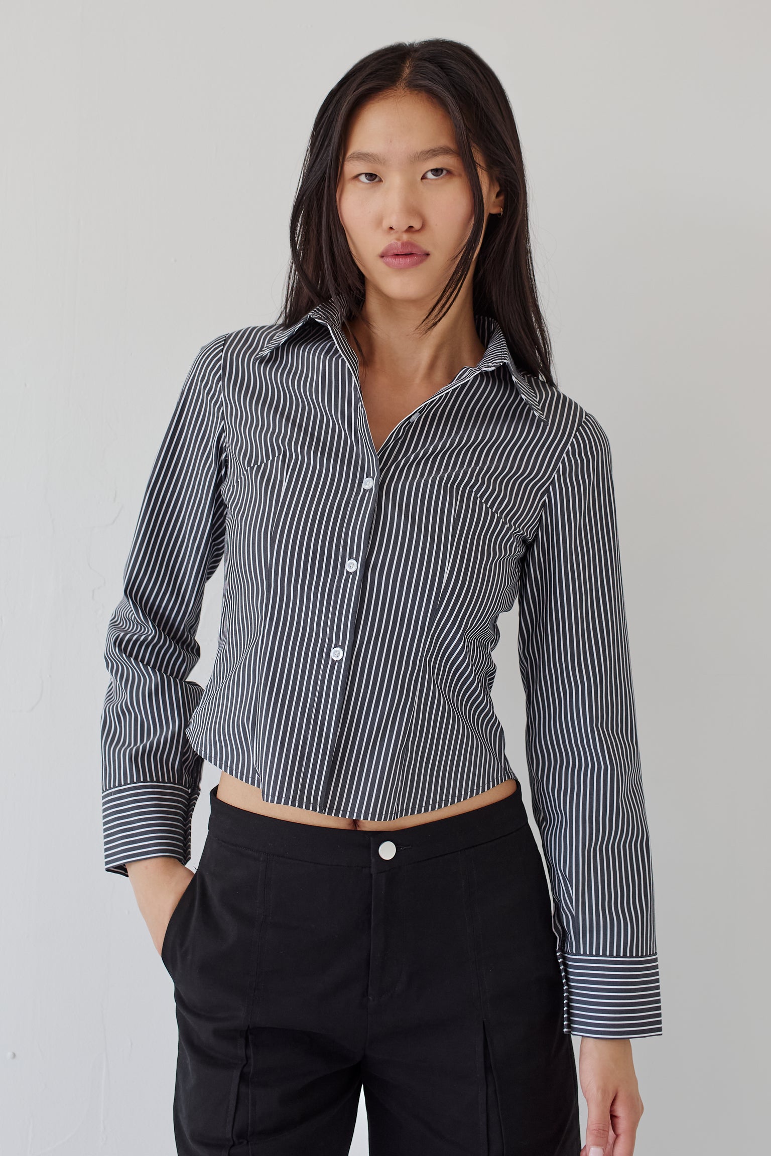 Woman wearing a black and white striped shirt paired with black pants against a plain background