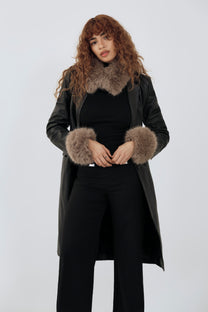 model wearing an all black outfit with a taupe fur scarf and cuffs against a plain background
