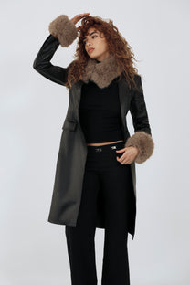 model wearing an all black outfit with a taupe fur scarf and cuffs against a plain background