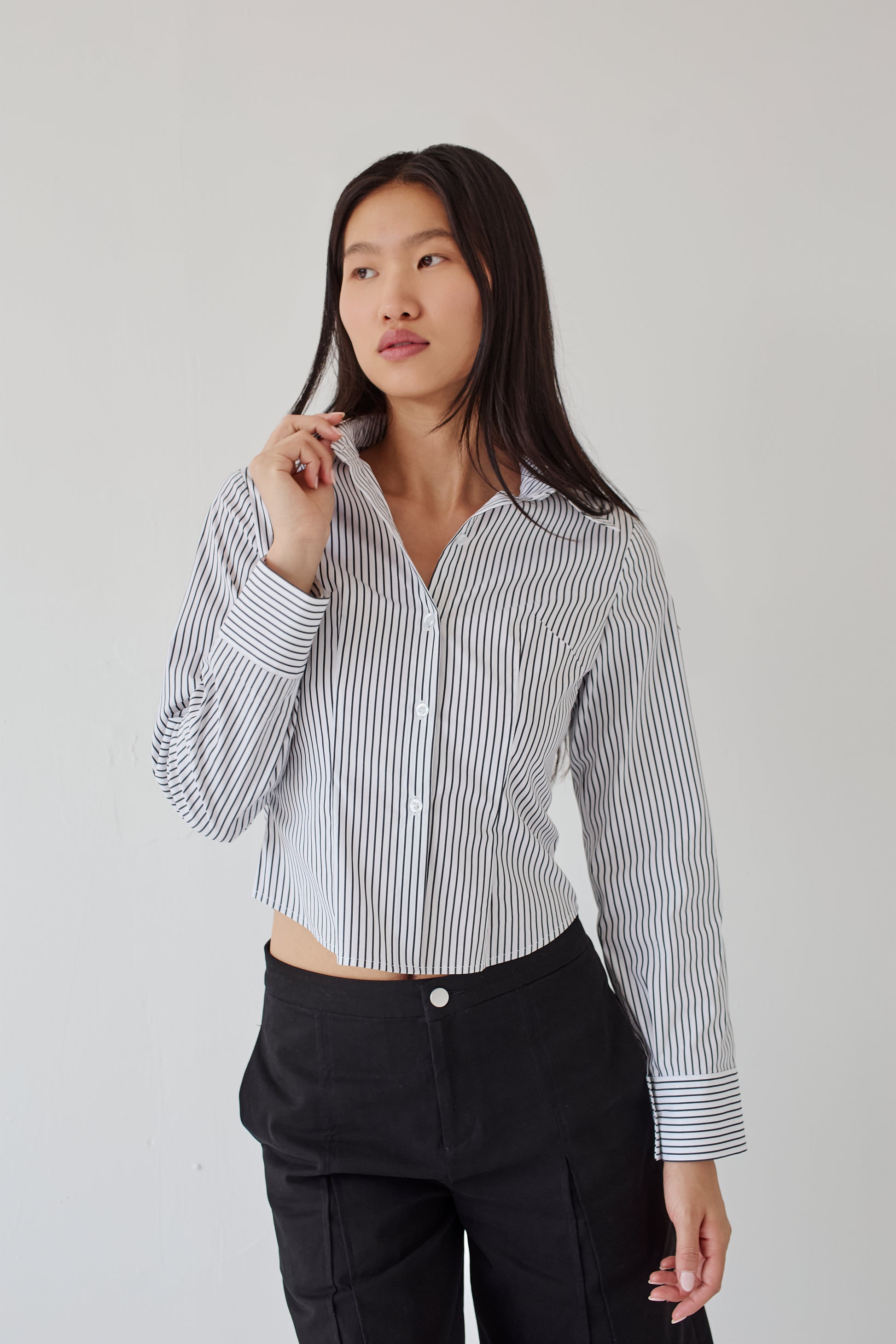 Woman wearing a black and white striped shirt with black pants on a plain background
