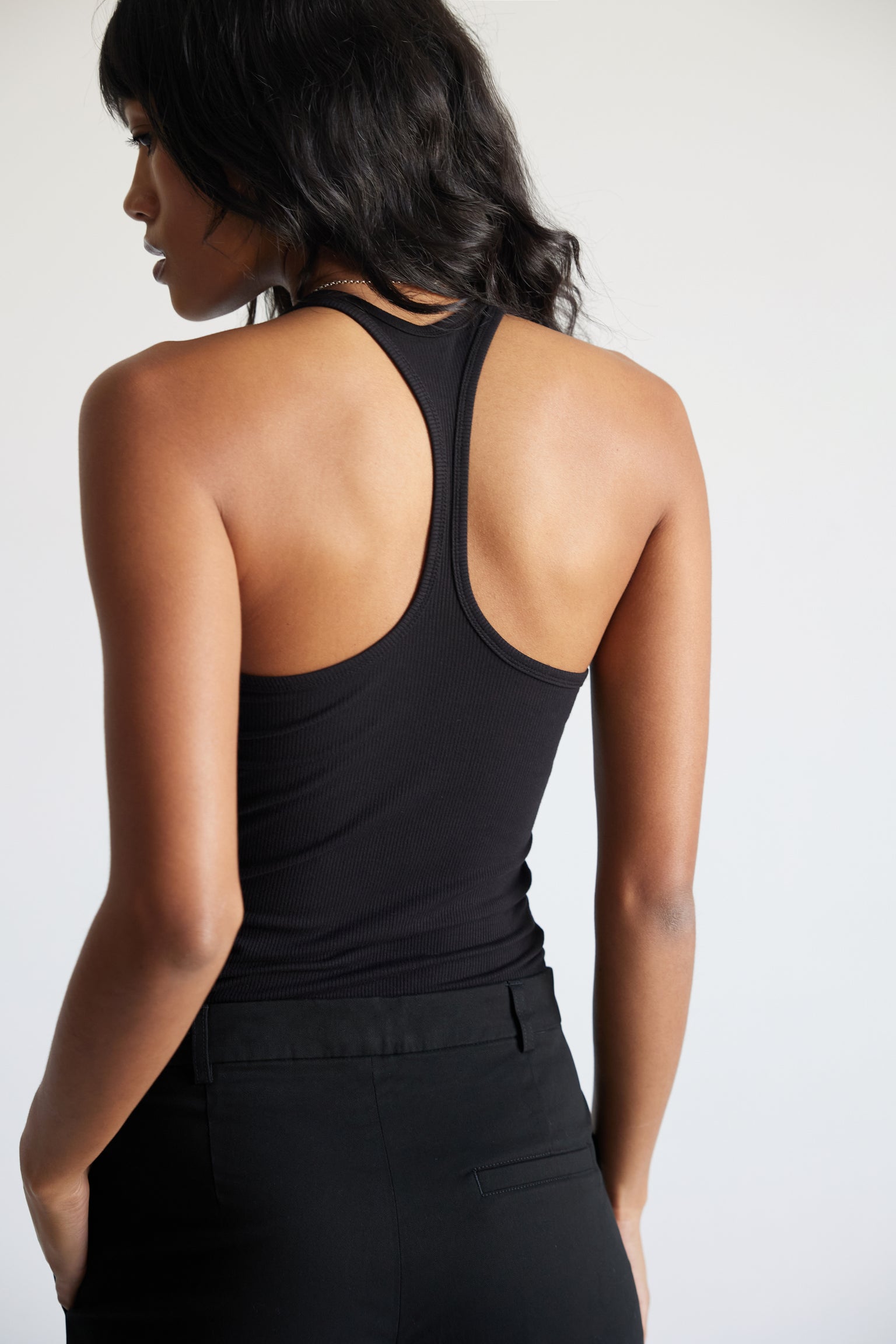 Woman wearing a black tank top against a plain background