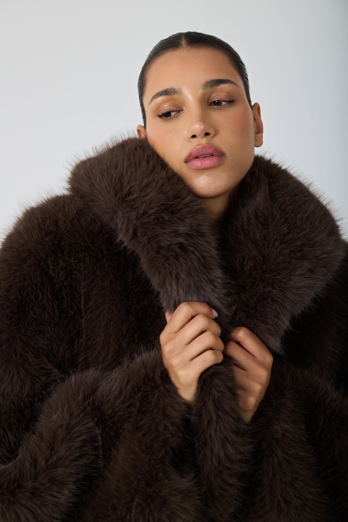 model wearing a brown fur coat against a blank background