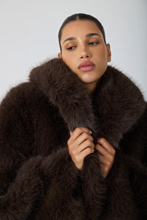 model wearing a brown fur coat against a blank background