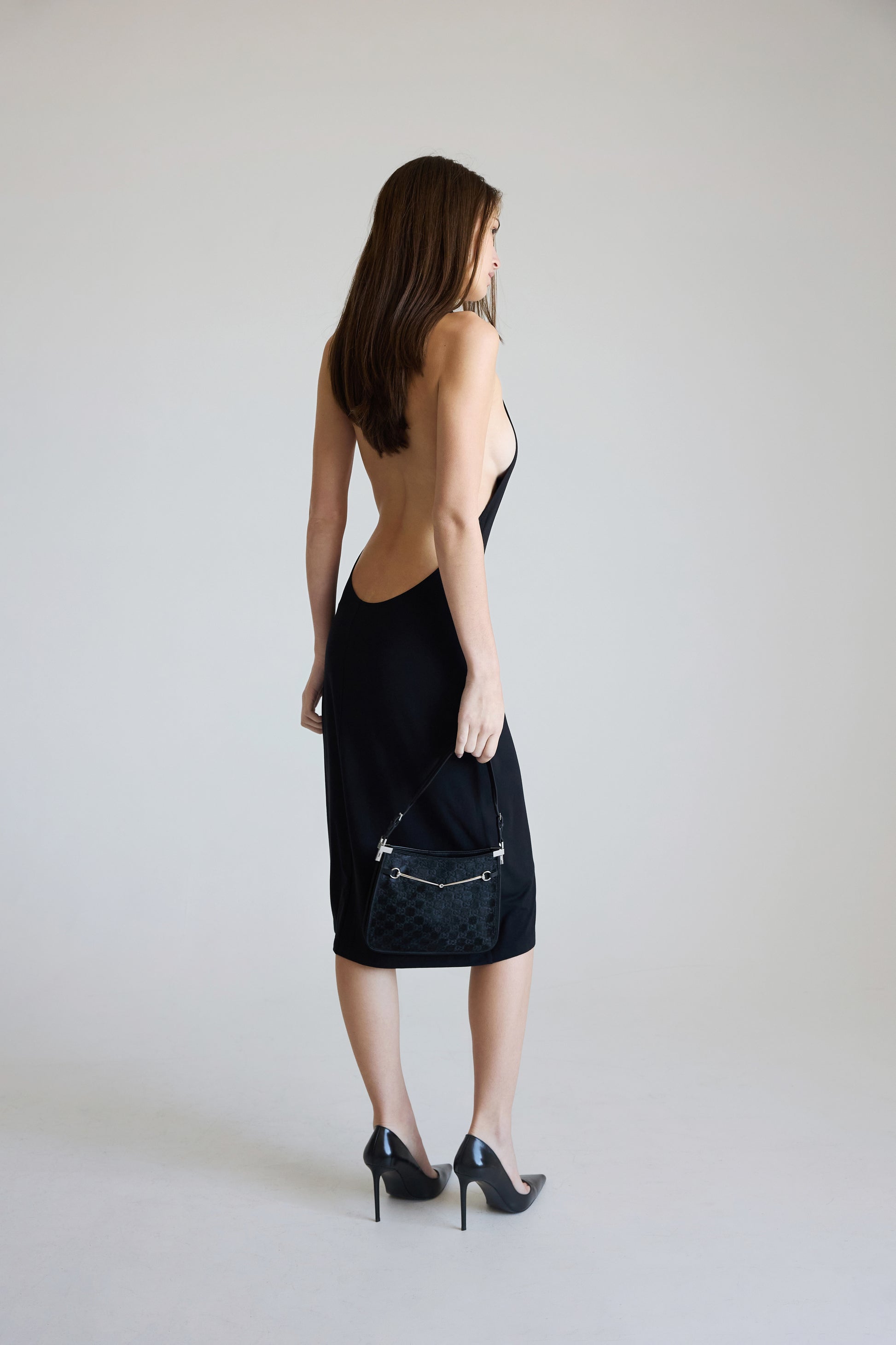 Woman wearing a black dress with cut-out back on a plain background