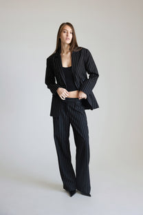 Woman wearing a black pinstripe suit on a plain background