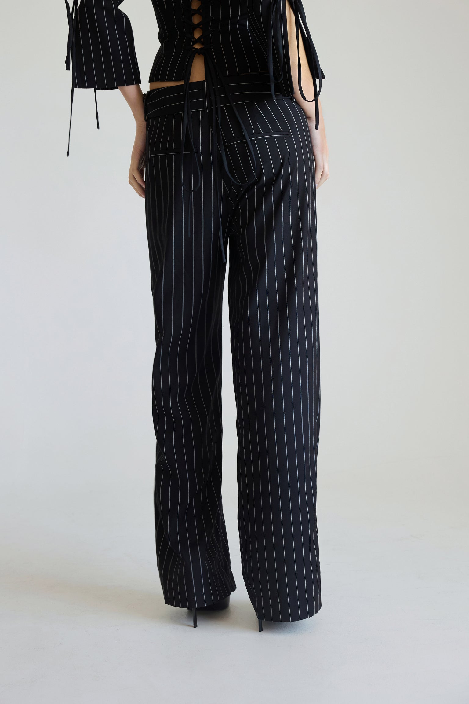 Woman wearing black pinstripe pants on a white background