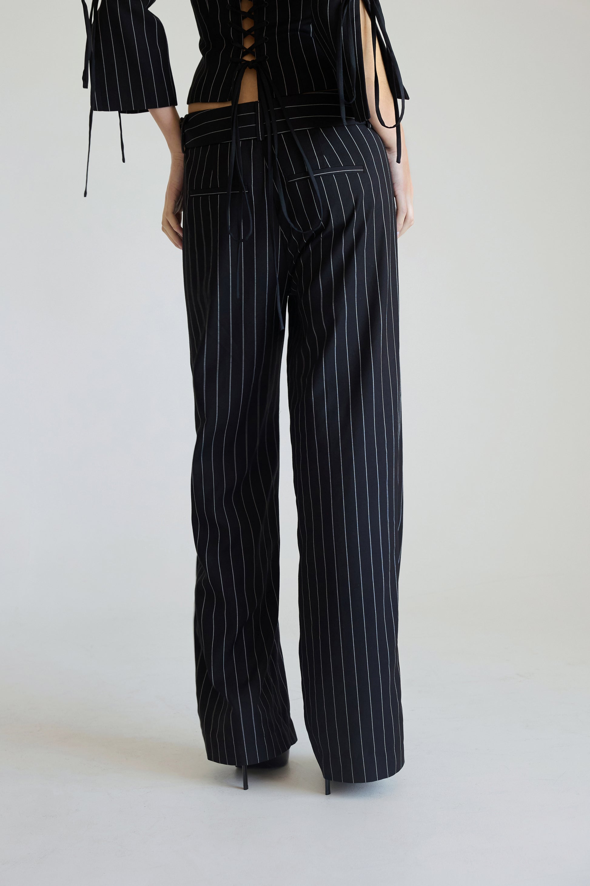 Woman wearing black pinstripe pants on a white background