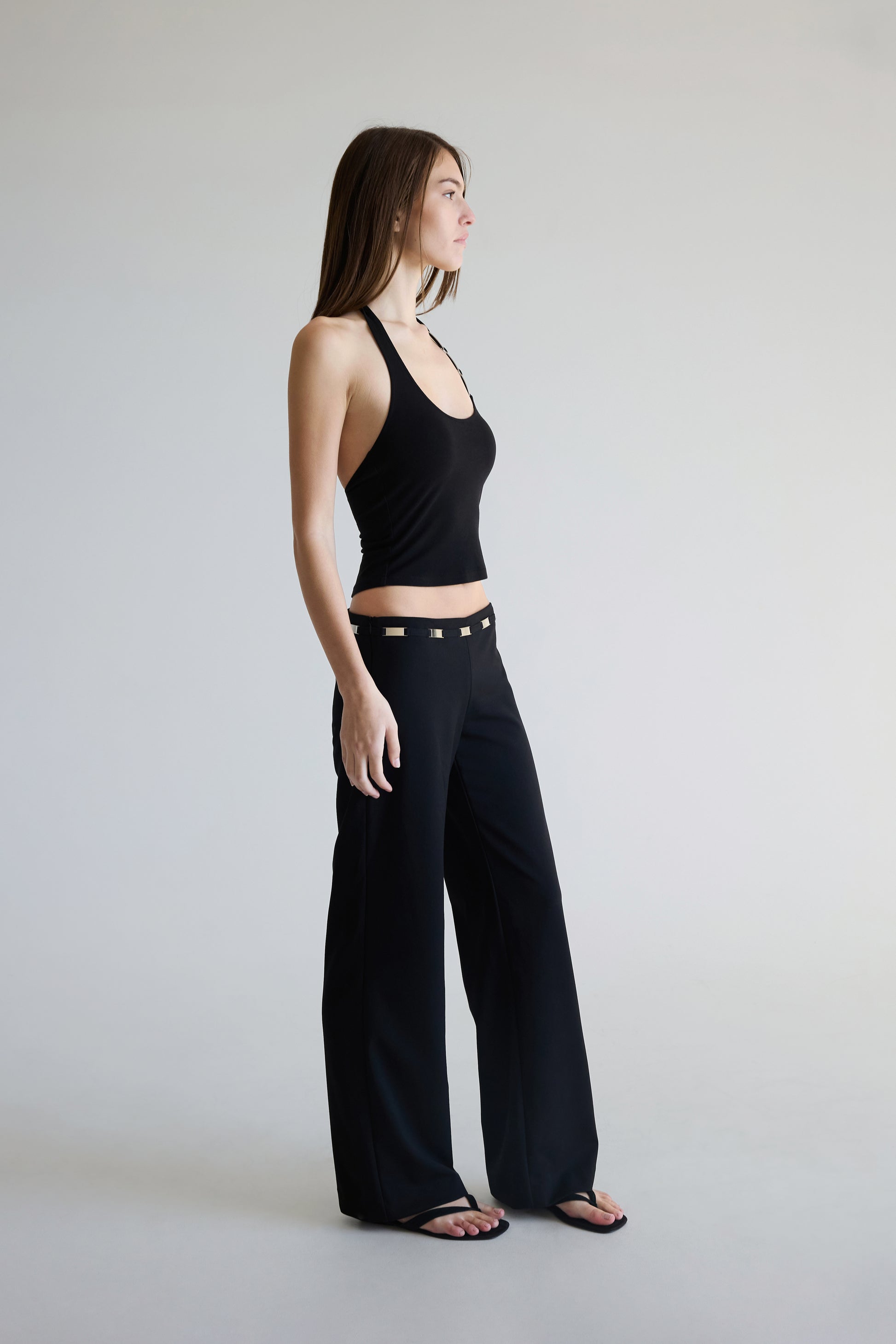 Woman wearing a black halter top and black pants against a plain background