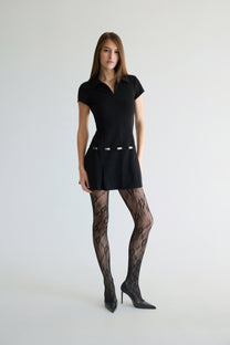 Woman wearing a black dress and patterned stockings on a white background