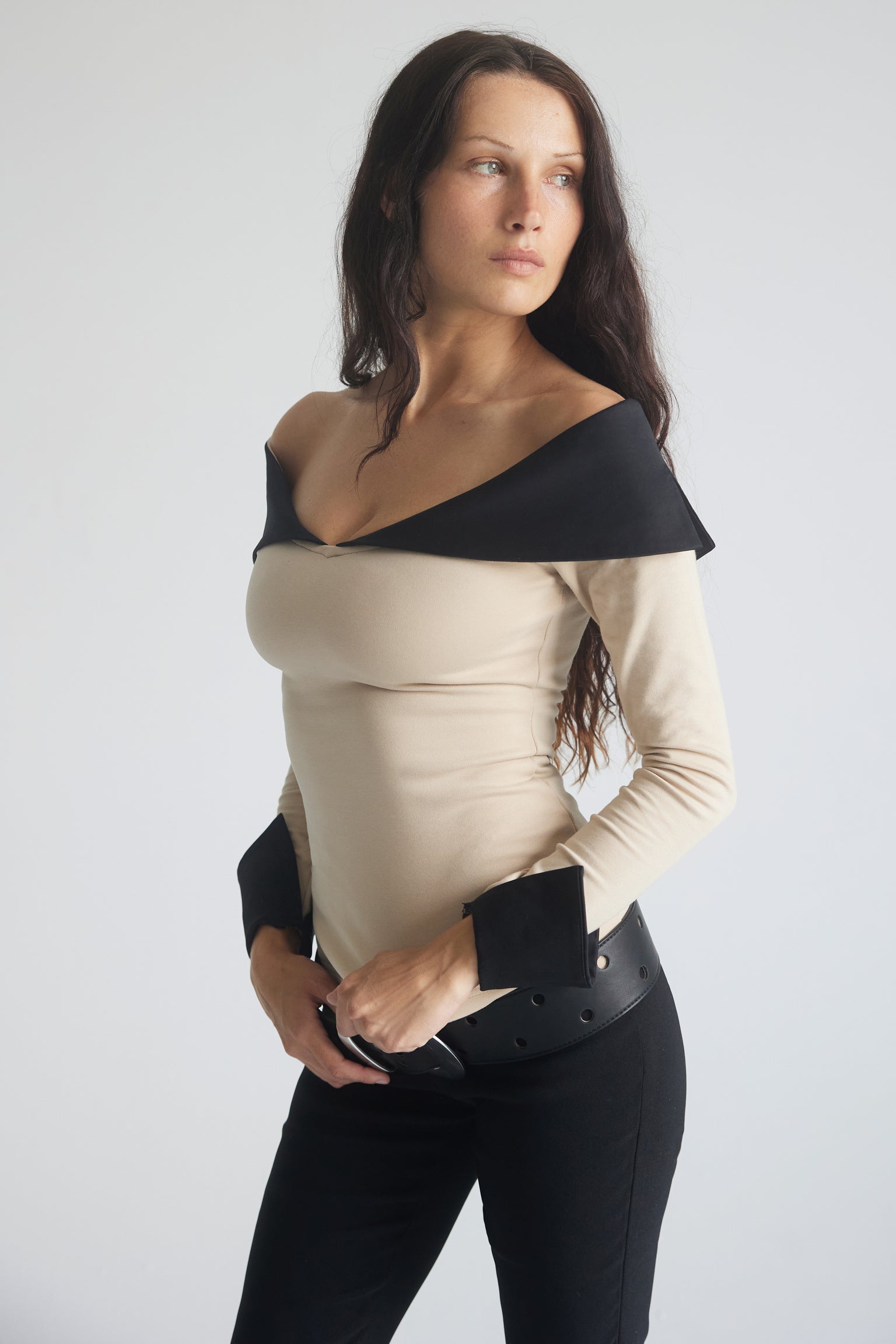 A woman wearing a long sleeve top with an off-shoulder neckline and contrasting black collar and cuffs.