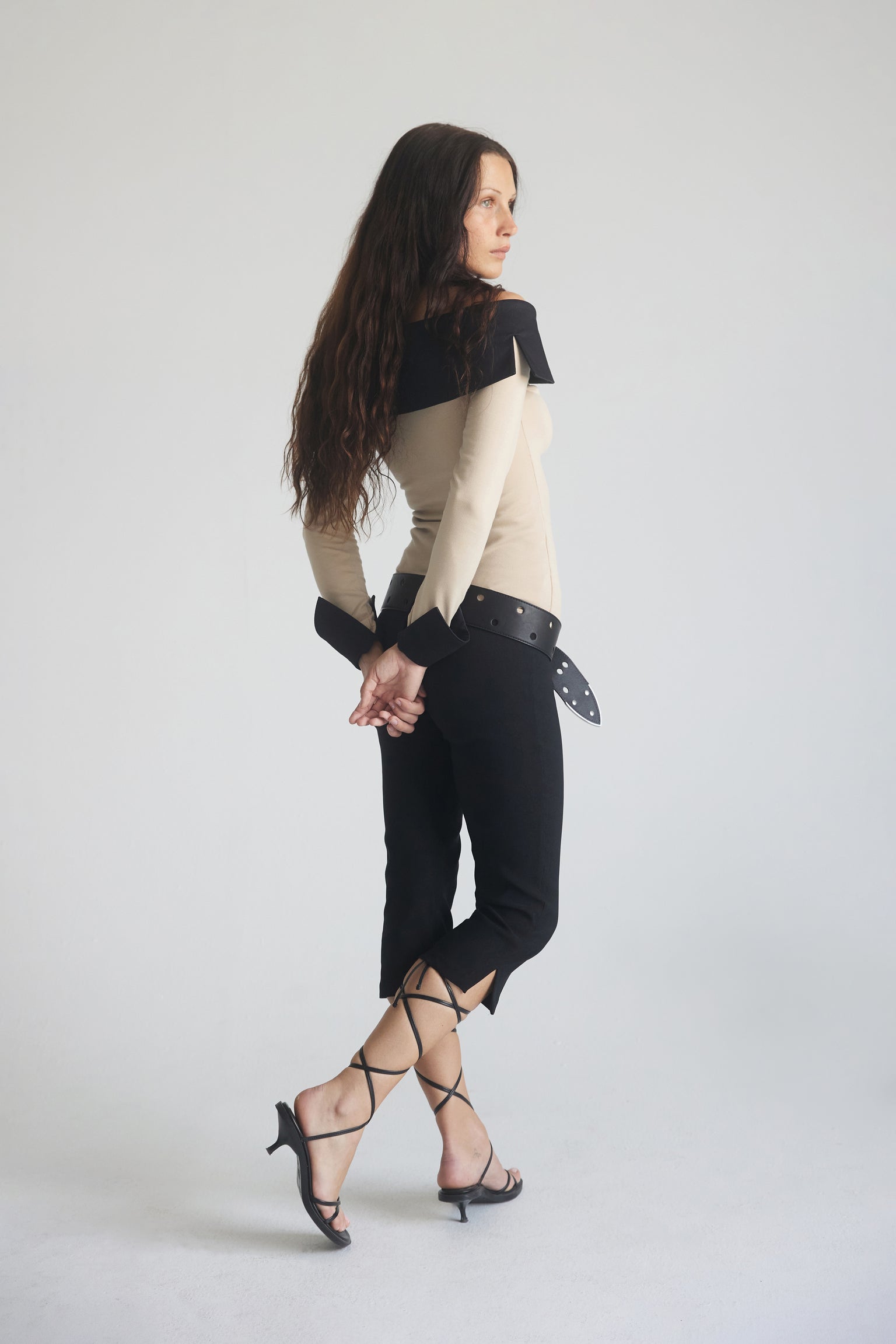 A woman wearing a long sleeve top with an off-shoulder neckline and contrasting black collar and cuffs paired with black capri pants.