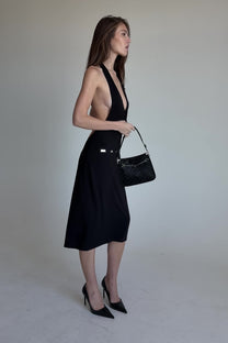 Woman wearing a black halter dress against a plain background